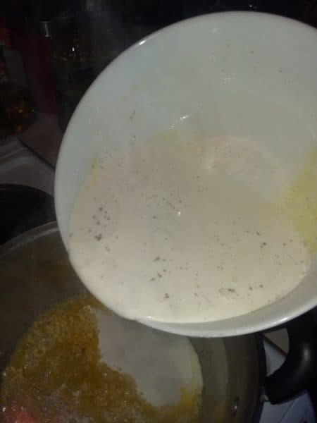 Alfredo sauce pouring into pot