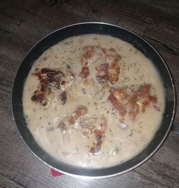 chicken thighs with mushroom sauce in frying pan