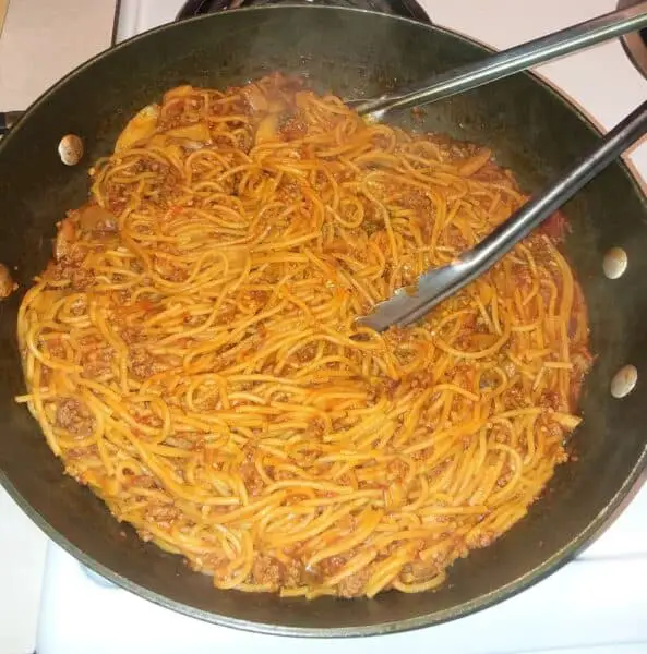 spaghetti in a pot with tongs