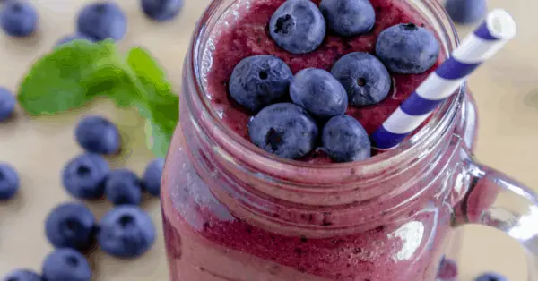 blueberry smoothie in a mason jar topped with blueberries